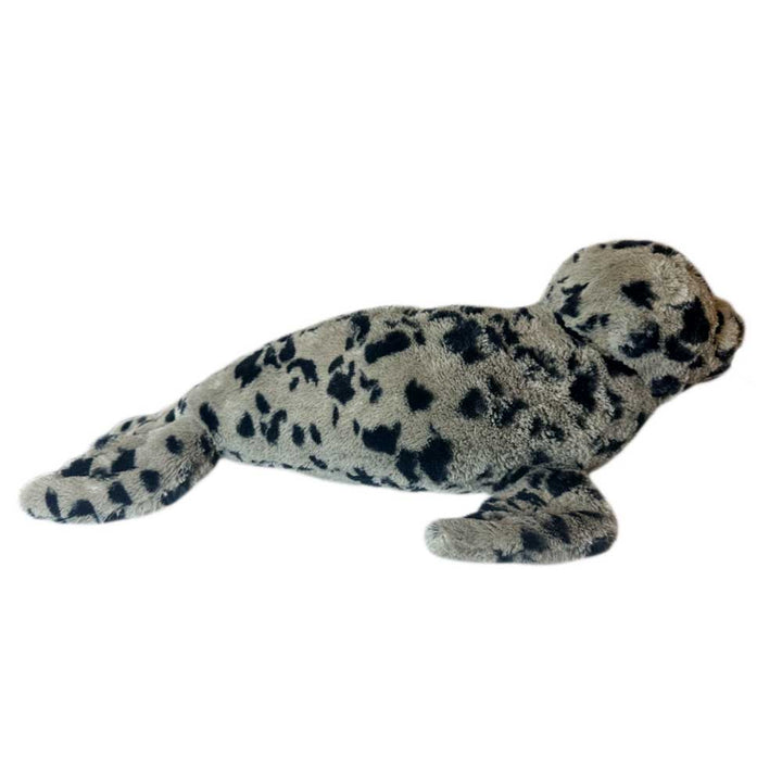 The Earth Pal Harbor Seal Plush is a soft, light grey plush toy with black spots, lying flat with extended flippers and tail—crafted from eco-friendly recycled materials.