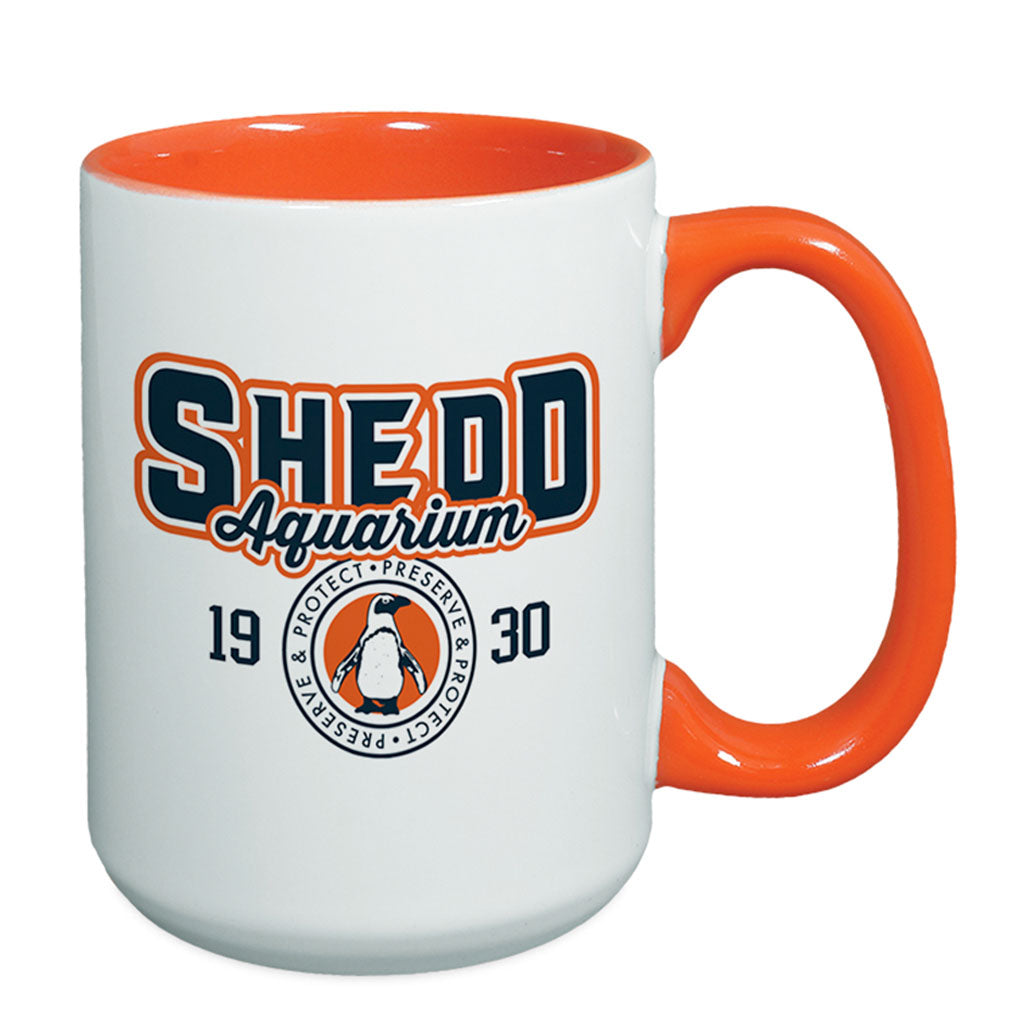 The Shedd Aquarium Sporty Two-Tone Mug features an orange interior and handle, bold Shedd Aquarium lettering, "1930," and a penguin logo with "Protect - Preserve." A standout ceramic piece for any collection.