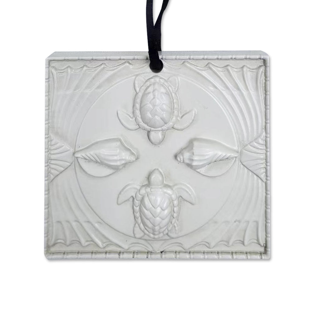 The Shedd Aquarium Ceiling Tile Ornament is a translucent rectangular decoration embossed with two sea turtles, two seashells, and wave patterns, hung by a black ribbon—an elegant gift for marine life lovers.