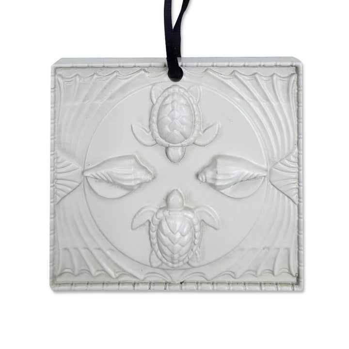 The Shedd Aquarium Ceiling Tile Ornament is a translucent rectangular decoration embossed with two sea turtles, two seashells, and wave patterns, hung by a black ribbon—an elegant gift for marine life lovers.