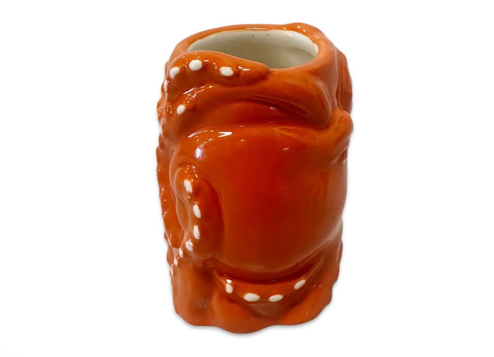 The 3D Octopus Shot Glass is a ceramic shot glass shaped and painted like an orange octopus with white accents, featuring sculpted tentacles wrapping around the sides and set against a white background.