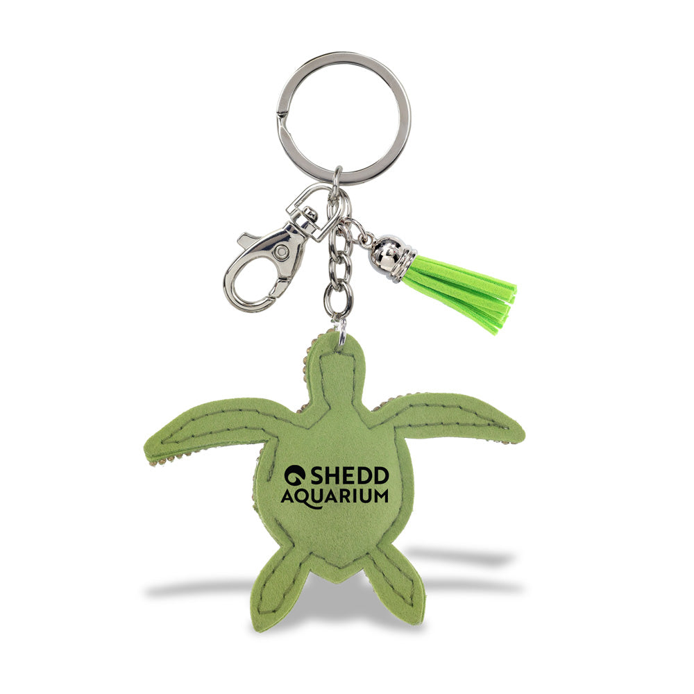 The Shedd Aquarium Sea Turtle Bling Keychain features a green turtle design with a silver key ring, metal clasp, and green tassel—displayed on a white background.