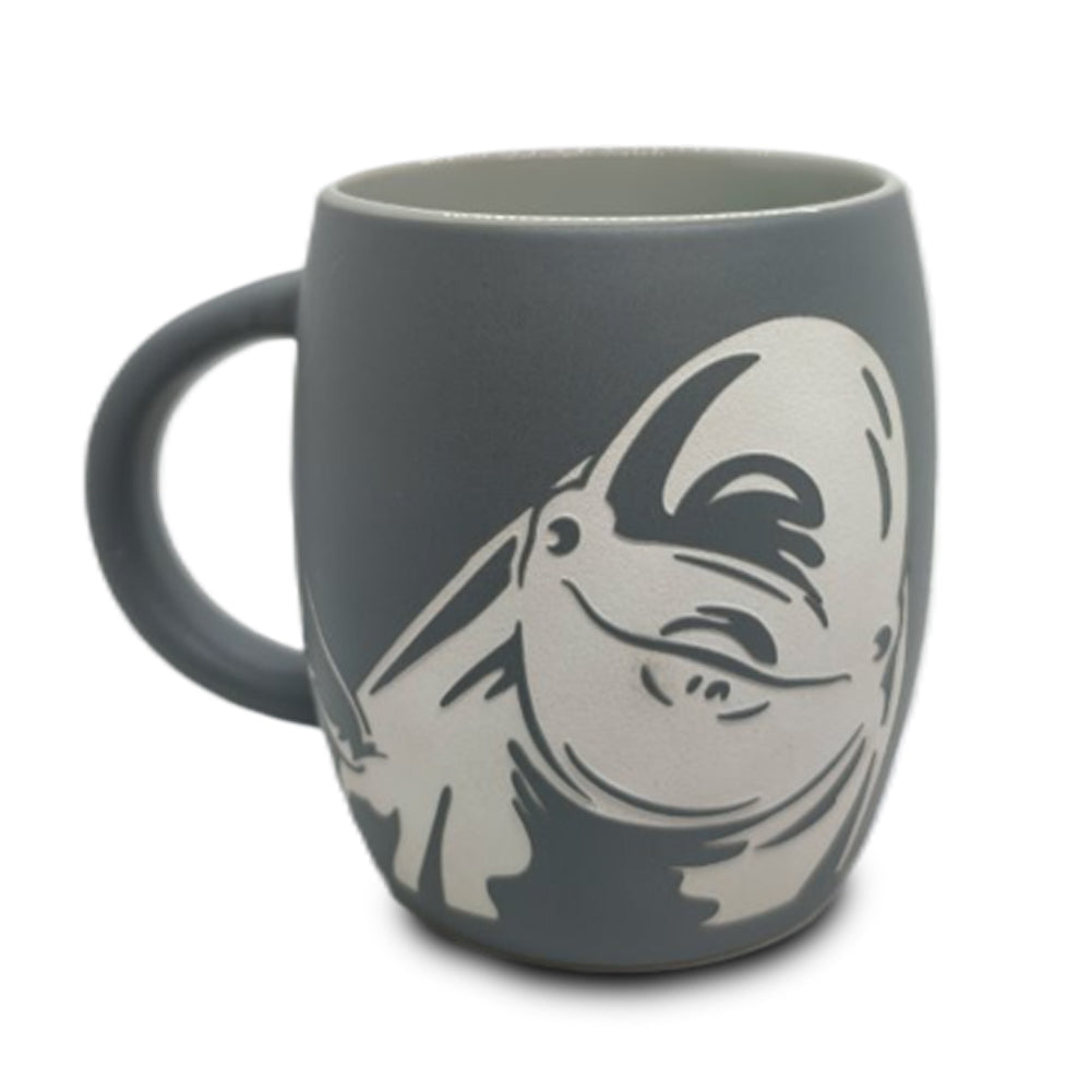 Introducing the Shedd Aquarium Beluga Etched Mug: a gray ceramic mug featuring a finely etched white outline of a smiling beluga, perfect for marine life conservation enthusiasts or as a thoughtful keepsake after visiting iconic destinations like Shedd Aquarium.