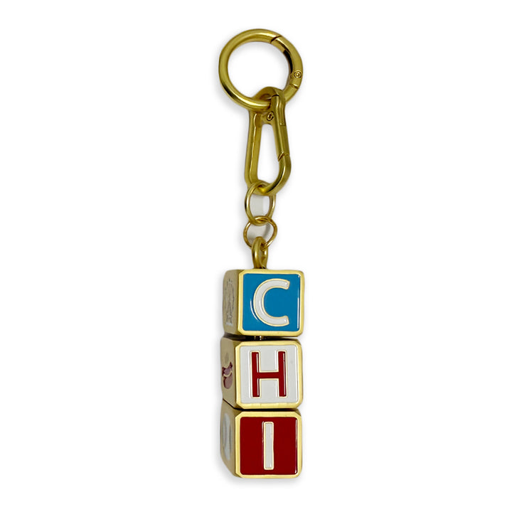 The Chicago Block Spinner Bag Charm is a gold keychain featuring three stacked alphabet blocks spelling CHI, with each block in a different color—blue, white, and red—making it the perfect Chicago accessory for your keys or as a stylish bag charm.