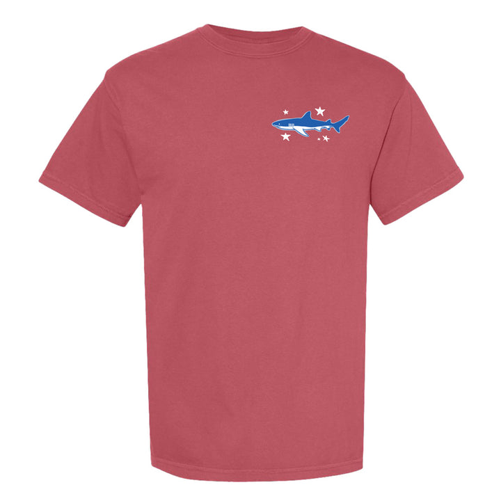 The Shedd Aquarium Sea to Shining Sea T-Shirt is a red short-sleeve tee with a small blue shark and four white stars graphic on the left chest, inspired by America's 250th birthday.