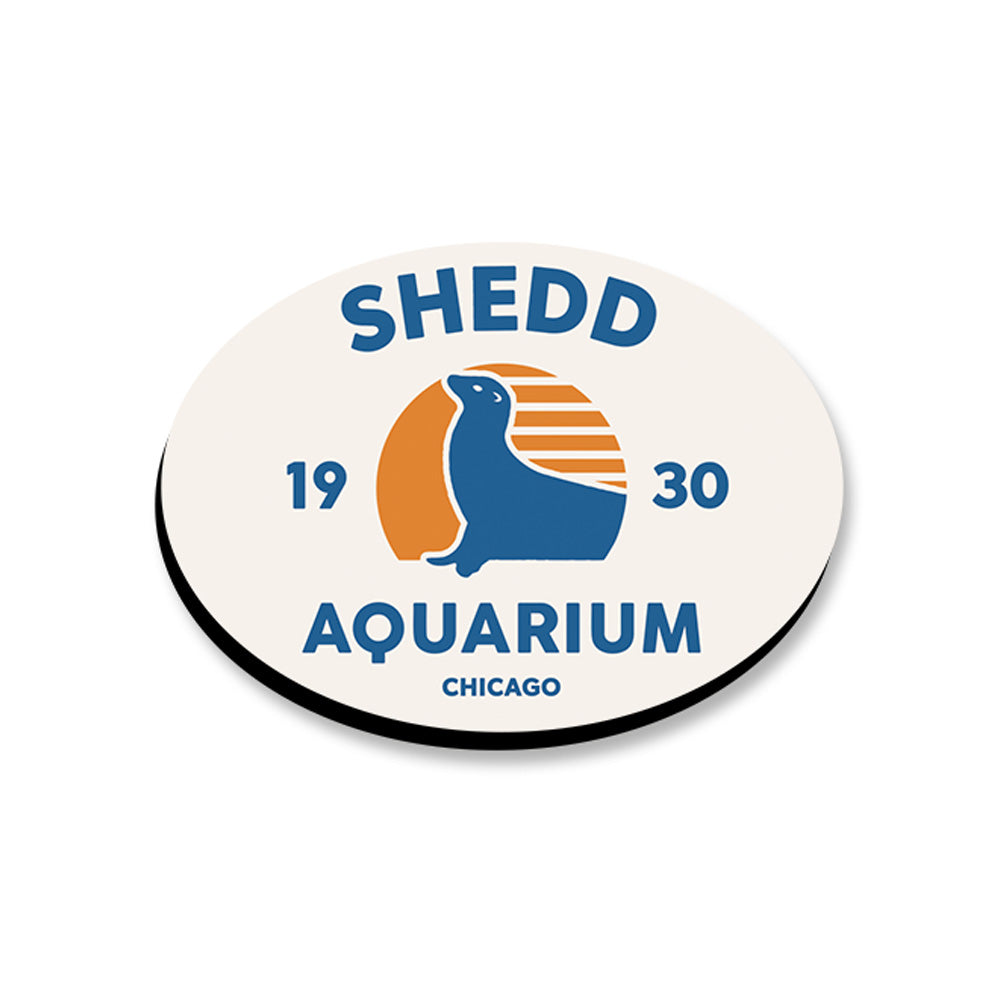 The Shedd Aquarium Sea Lion 2D Magnet shows a blue sea lion silhouette against an orange sun and reads “Shedd Aquarium Chicago 1930” in blue and orange—a perfect marine-themed keepsake.