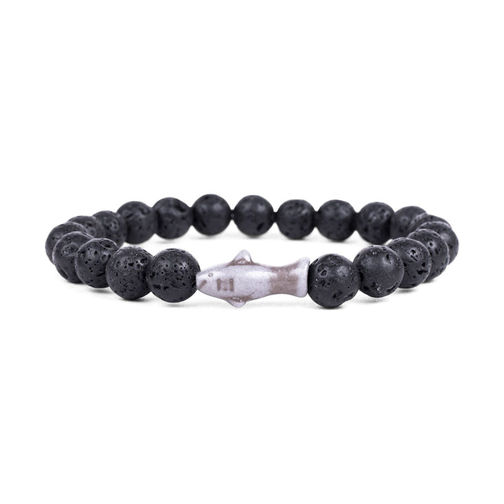 The Fahlo Shark Tracking Bracelet features round black lava stones with a metallic shark-shaped bead at the center, shown on a white background.
